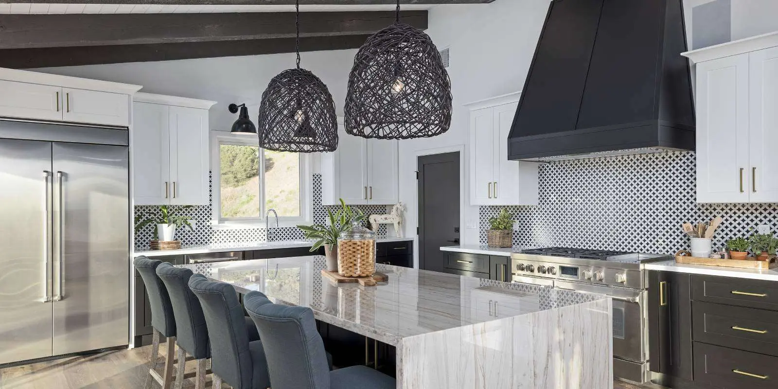 White kitchen with a marble island, black range hood and woven pendant lights